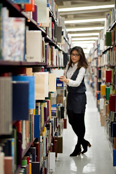 istock Woman reading a book at the library 493539701