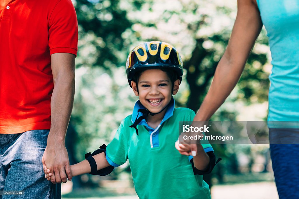 Active family time Cute boy having fun with his parents, roller skating in the park 2015 Stock Photo