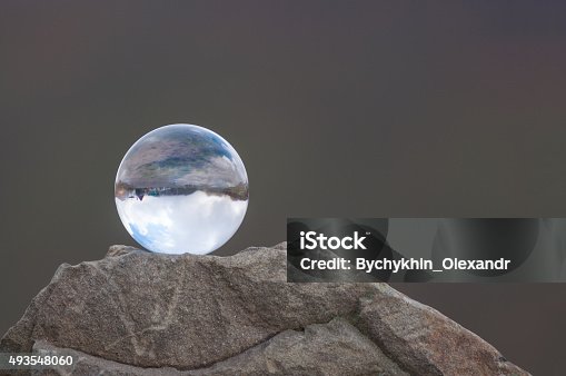istock Glass transparent ball on the top of rock and dark 493548060