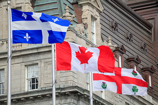 Quebec, Canadian and Montreal flags waving with the foreground of City Hall of Montreal, Quebec, Canada