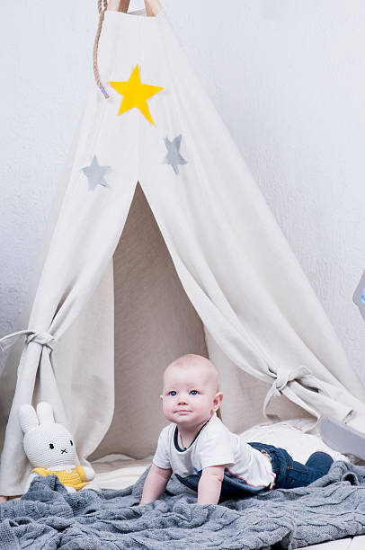 istock Cute baby creeps on gray knitted carpet 493553068