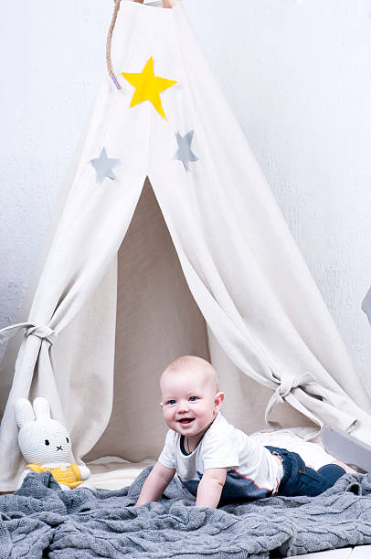 istock Cute baby creeps on gray knitted carpet 493553086