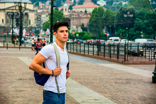 Handsome young man walking in European city square