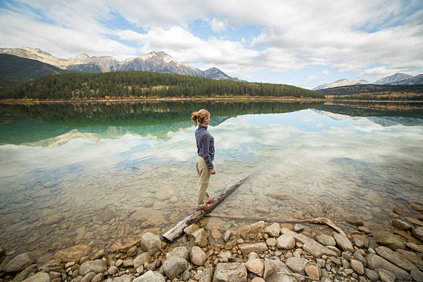 istock Woman standing on tree log above lake 493562894