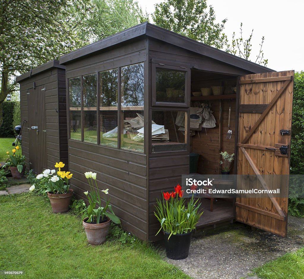 Garden shed exterior with open door, tools, and plants. Garden shed exterior in Spring, for gardening and outdoor lifestyles. Shed Stock Photo