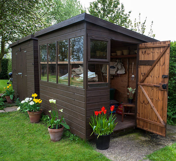 Garden shed exterior with open door, tools, and plants. Garden shed exterior in Spring, for gardening and outdoor lifestyles. shed stock pictures, royalty-free photos & images