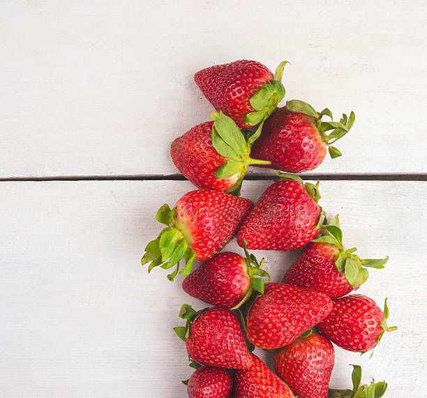 istock strawberries lying on white wooden table 493571695