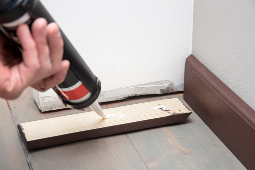 home improvement, pushing glue on the wooden baseboard