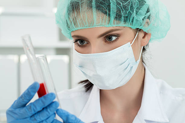 travailleur de laboratoire de femmes à la recherche sur deux flasks avec un liquide rouge - medical exam science research scientific experiment photos et images de collection