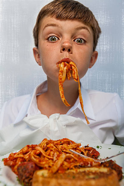jovem rapaz goza de uma mouthful de esparguete - hqlypse imagens e fotografias de stock