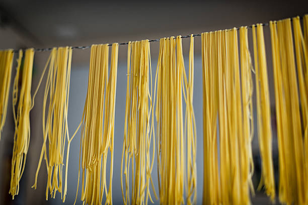 esparguete caseiras massa linguini de pendurado no cabo de secagem - zubereiten imagens e fotografias de stock