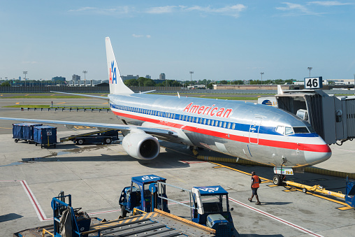 New York, USA - July 10, 2015: An America Airlines plane sitting at gate 46 at JFK airport late in the day as ground crew finish up before take off.