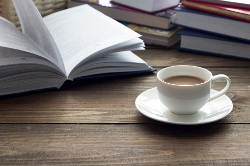 cup of coffee and a lot of books on the table