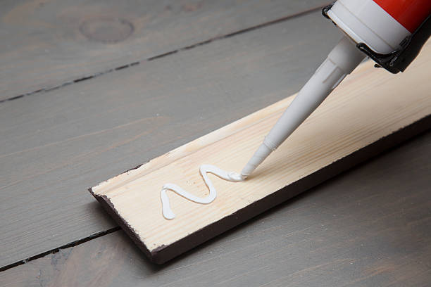 putting glue on a piece of wooden baseboard putting glue from tube on a piece of wooden baseboard solvent stock pictures, royalty-free photos & images