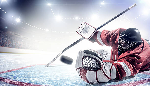 Ice Hockey Goalie Ice hockey goalie trying to catch puck during game in indoor arena full of spectators. ice hockey stock pictures, royalty-free photos & images