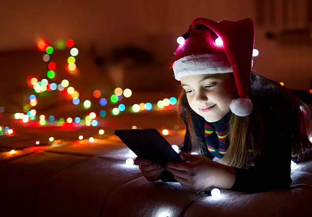 Photo of Child in christmas hat with tablet