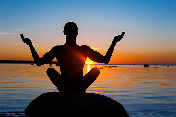 istock Meditating man silhouette on multicolored sunset background. 493585926
