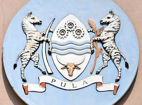 Coat of arms of Botswana at the parliament - shield with cog wheels, waves and bull's head - zebras holding elephant's tusks - 'Pula' means rain in Setswana - National Assembly of Botswana - Government Enclave - Gaborone,  Botswana