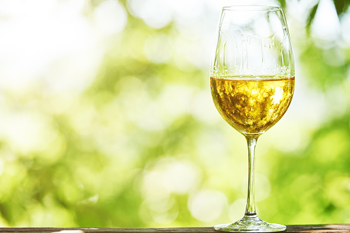 Glass of Chardonnay, Sauvignon or Rkatsiteli white wine over outdoors background 