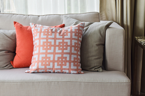 Chinese pattern in orange and deep orange and gray pillows on light gray sofa set