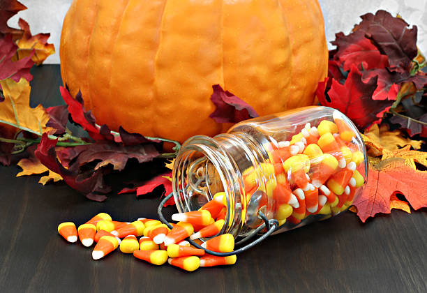 candy mais in un barattolo per conserve e marmellate spilling su un tavolo. - candy halloween candy corn jar foto e immagini stock