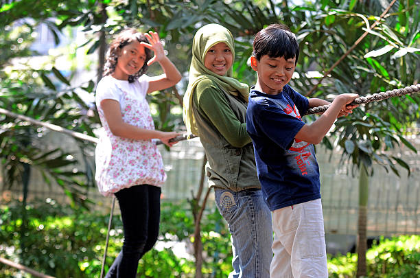 Surabaya, Indonesia - July 4, 2013: Some young climbers rope in the Kebun Bibit, garden city of Surabaya, East Java, Indonesia on July 4th, 2013. Kebun bibit is an attractive garden with a variety of plants and tropical trees. Less than a thousand trees grow there so as to provide a cool atmosphere, comfortable and fresh air, which is located in the city center of Surabaya.