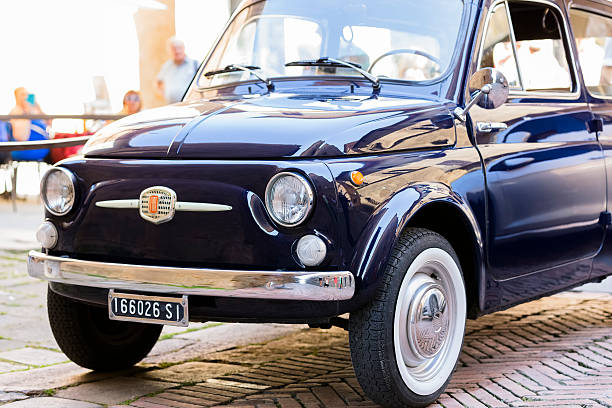 Montalcino, Italy - November 2, 2019: a traditionally Italian, classic Fiat 500 car, old style, is parked in an as well old district (the city centre) of the Tuscan town.