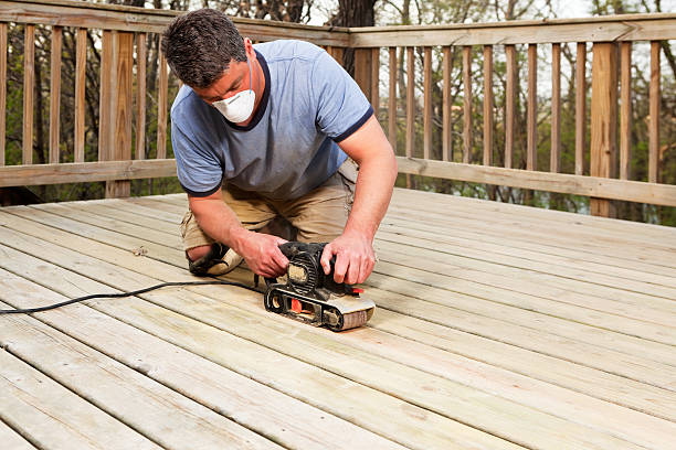 Worker with Belt Sander Sanding Deck Boards A worker is using a belt sander to sand and recondition weathered deck boards in preparation for staining. deck stock pictures, royalty-free photos & images