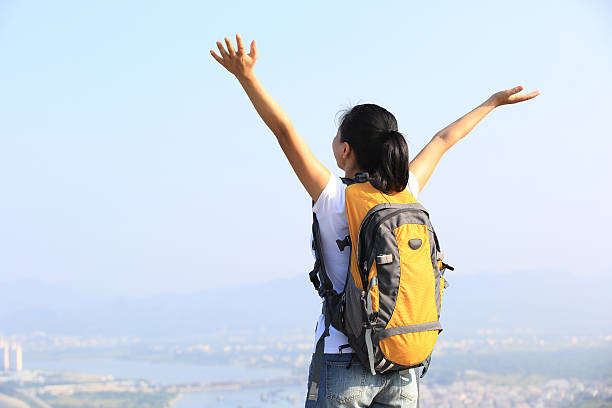 istock cheering woman hiker open arms at mountain peak 493610305