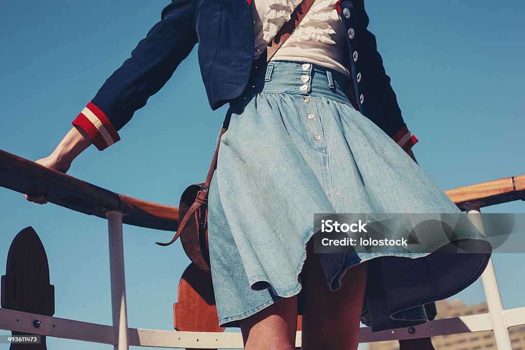 Young woman on the deck of ship with skirt blowing A young woman's skirt is blowing in the wind as she is standing on the deck of a boat cruising down the river Fashion Stock Photo