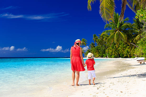 istock mother and son walk on summer beach 493618848