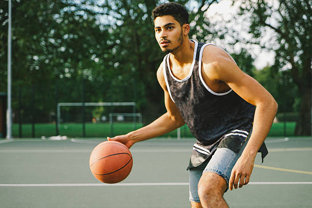 Basketball Player On The Court Facing Opponents Basketball player on the court facing opponents. dribbling stock pictures, royalty-free photos & images