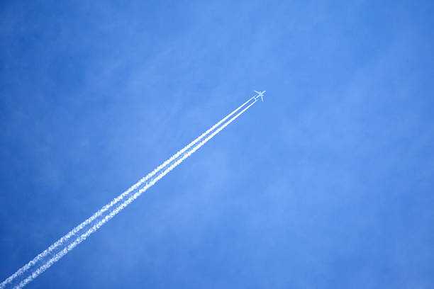 istock Passenger jet flying in clear blue sky, leaving white trail 493632162