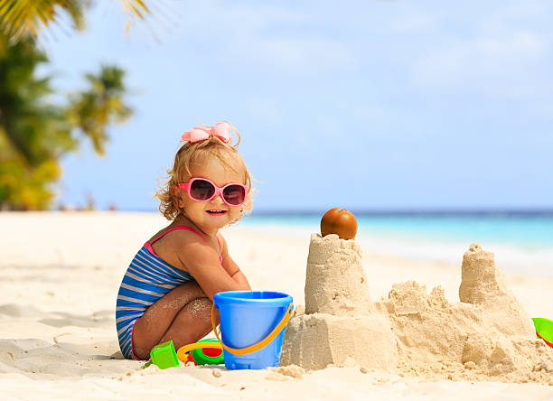 niedliche kleine mädchen spielen mit sand am strand - sandburg struktur stock-fotos und bilder