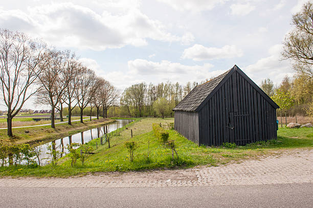 istock Black wooden shed near canal 493637997