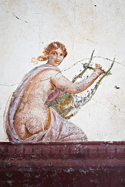 Detail of the fresco in Pompeii with woman playing a stringed instrument on a red background Pompeian
