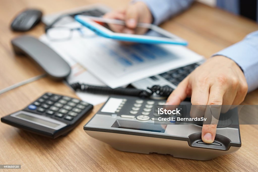 business man hanging up the phone while working on tablet very busy business man hanging up the phone while working on tablet computer, waiting for support Hanging Up Stock Photo