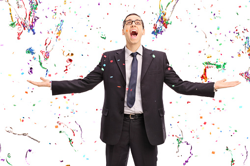 Studio shot of an overjoyed businessman standing in the middle of a lot of confetti streamers isolated on white background