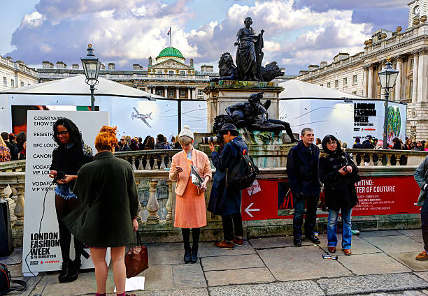 London Fashion Week London, United Kingdom - October 13, 2012: Group of people standing around in Somerset House in the afternoon for London Fashion Week, as a woman holds a microphone (left) getting ready to conduct an interview. london fashion week stock pictures, royalty-free photos & images