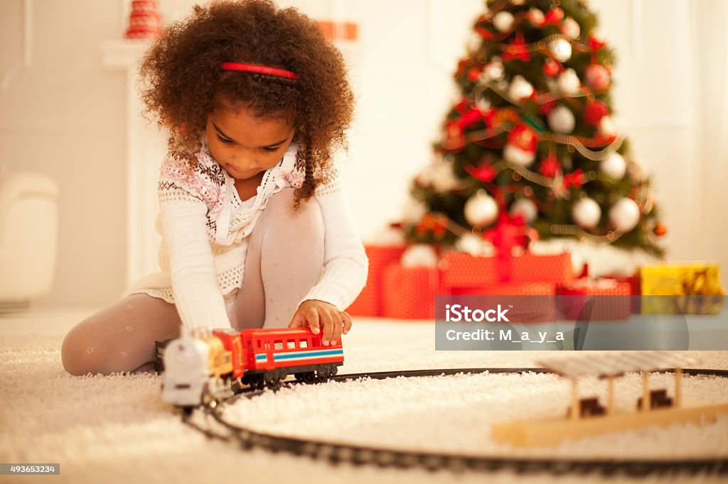 My new toy Cute girl enjoy playing with new toy by Christmas tree Child Stock Photo