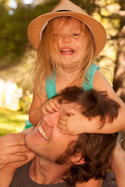 istock Father and daughter laughing while she rides on his shoulders 493653278