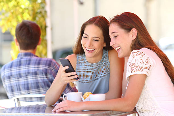 istock Two friends sharing a smart phone in a coffee shop 493656312