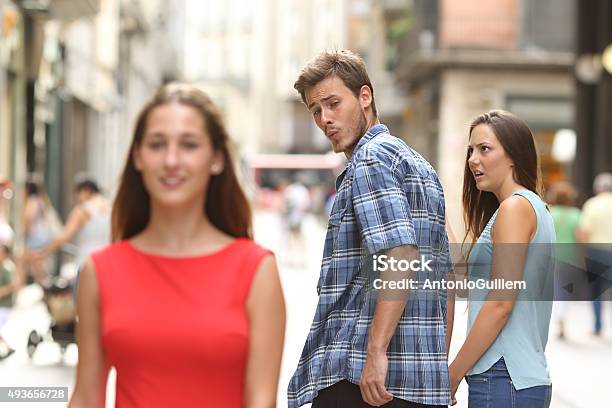 Disloyal Man With His Girlfriend Looking At Another Girl Stock Photo - Download Image Now
