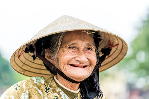 Old friendly vietnamese woman with typical vietnamese straw hat