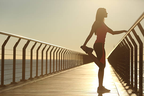 istock Woman silhouette exercising stretching on a bridge 493659570