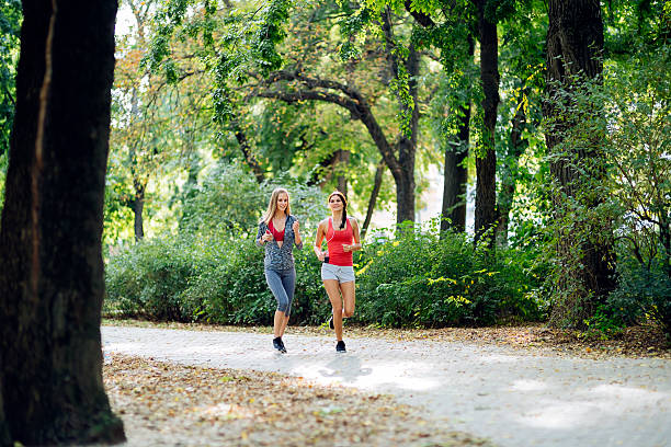istock Two beautiful women jogging in park 493659920