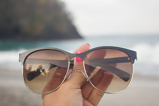 istock Woman hands holding sunglasses at the beach 493660010