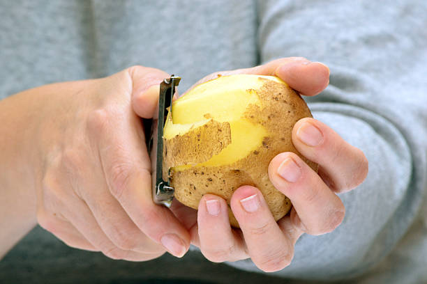 frau hände schälen kartoffeln - schälen essen zubereiten stock-fotos und bilder