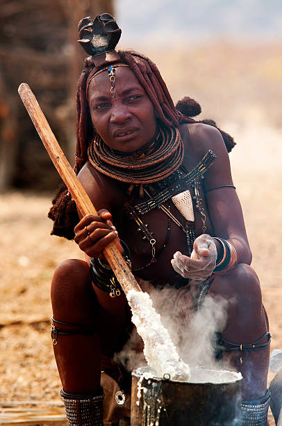 Epupa Falls, Namibia - August 23, 2010: Woman cooking his food in the open on his village, photo taked on the way to Epupa Falls, while visiting a himba village, Namibia. Himbas lives in Kunene region on northern Namibia in the Angola border, a very dry and wild region.