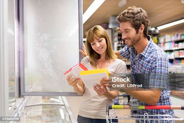 Young Couple Chooses Frozen Products In Supermarket Stock Photo - Download Image Now